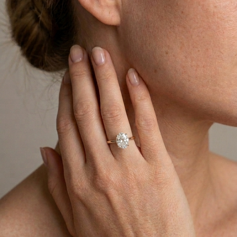 Close-up of a hand wearing a diamond ring with a neutral background