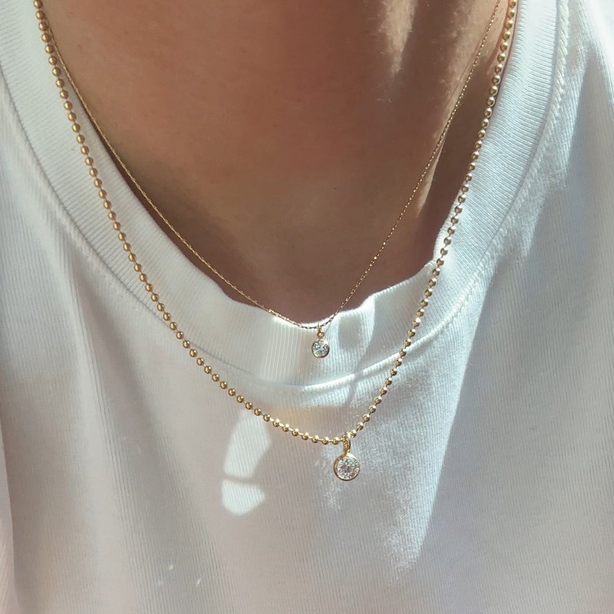 Gold necklace with small round pendants on a white shirt