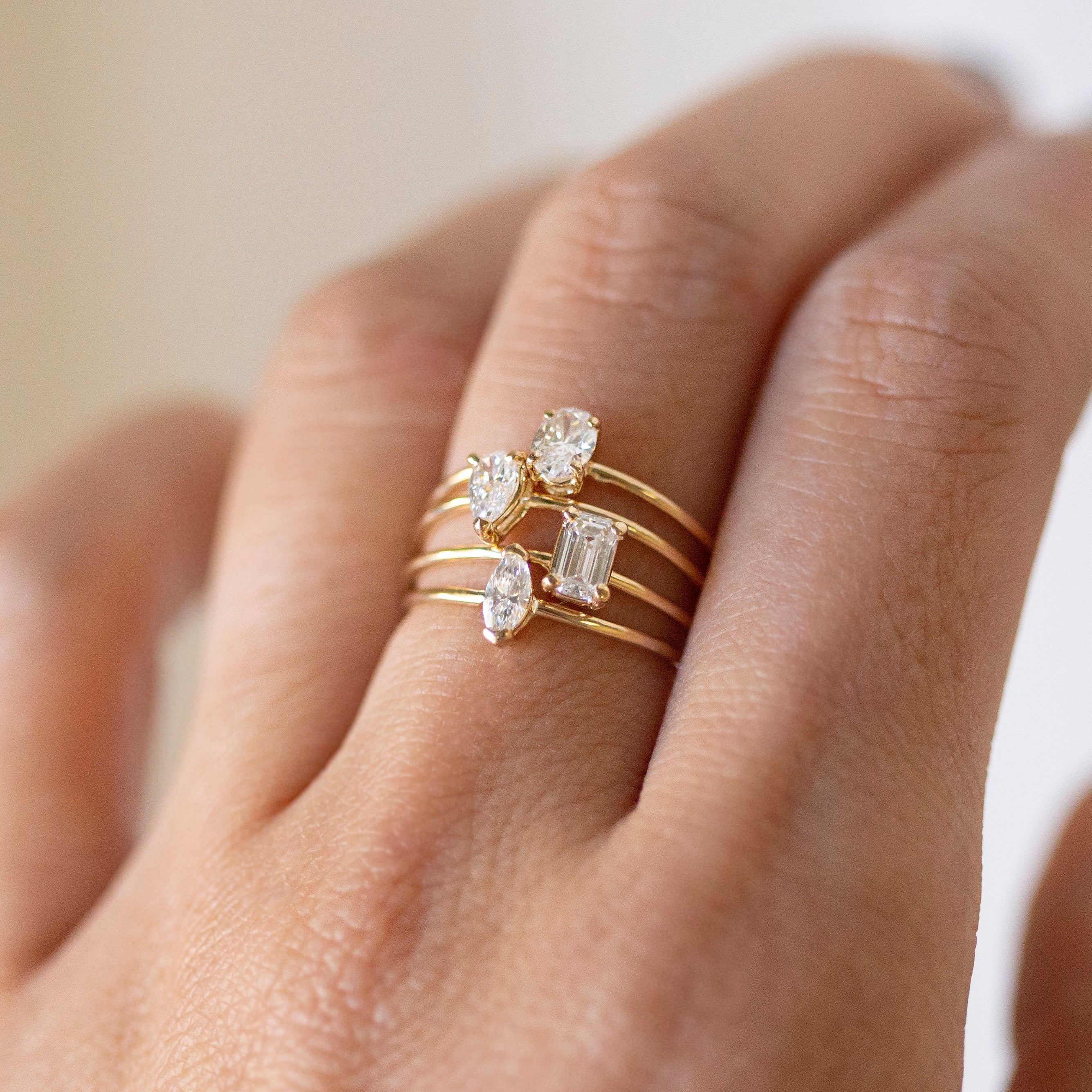 Gold ring with diamond accents on a hand against a neutral background