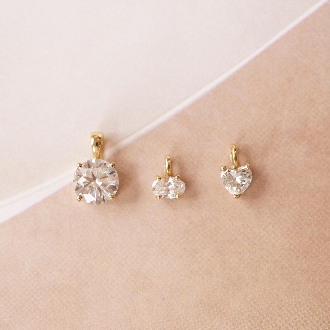 Set of gold earrings with clear gemstones on a beige surface