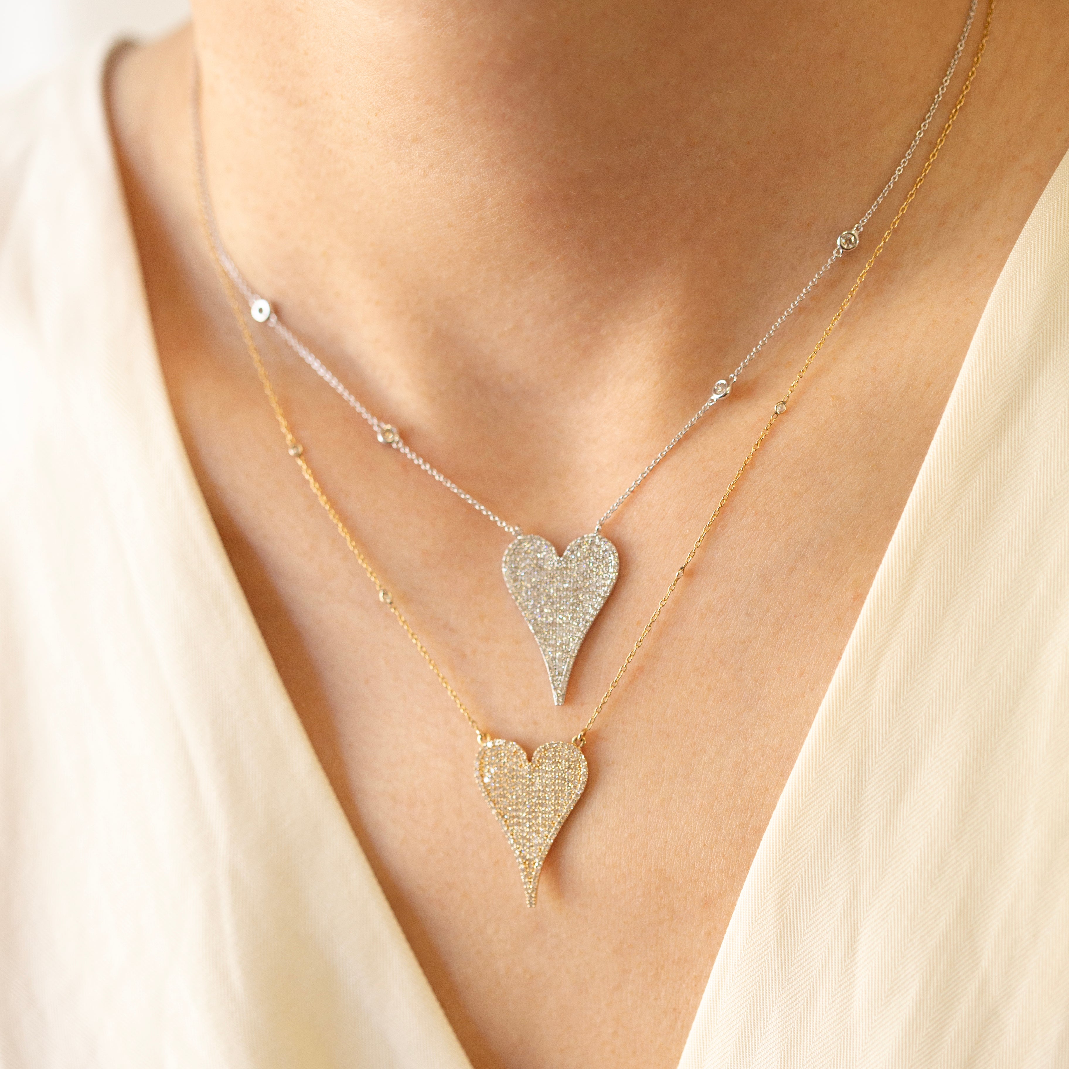 Necklace with heart-shaped pendants on a person wearing a light-colored top.