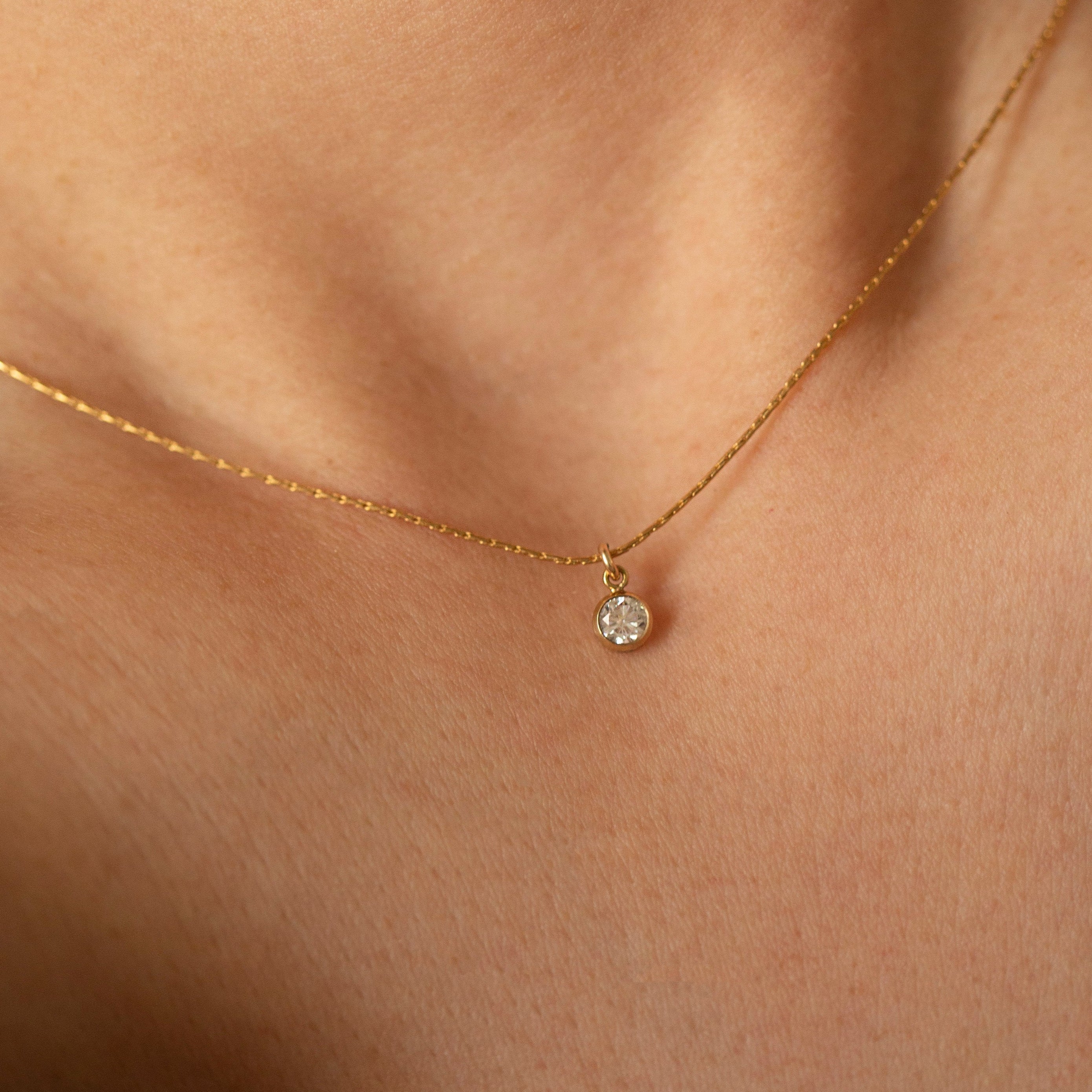 Gold necklace with a small pendant on a person's neck