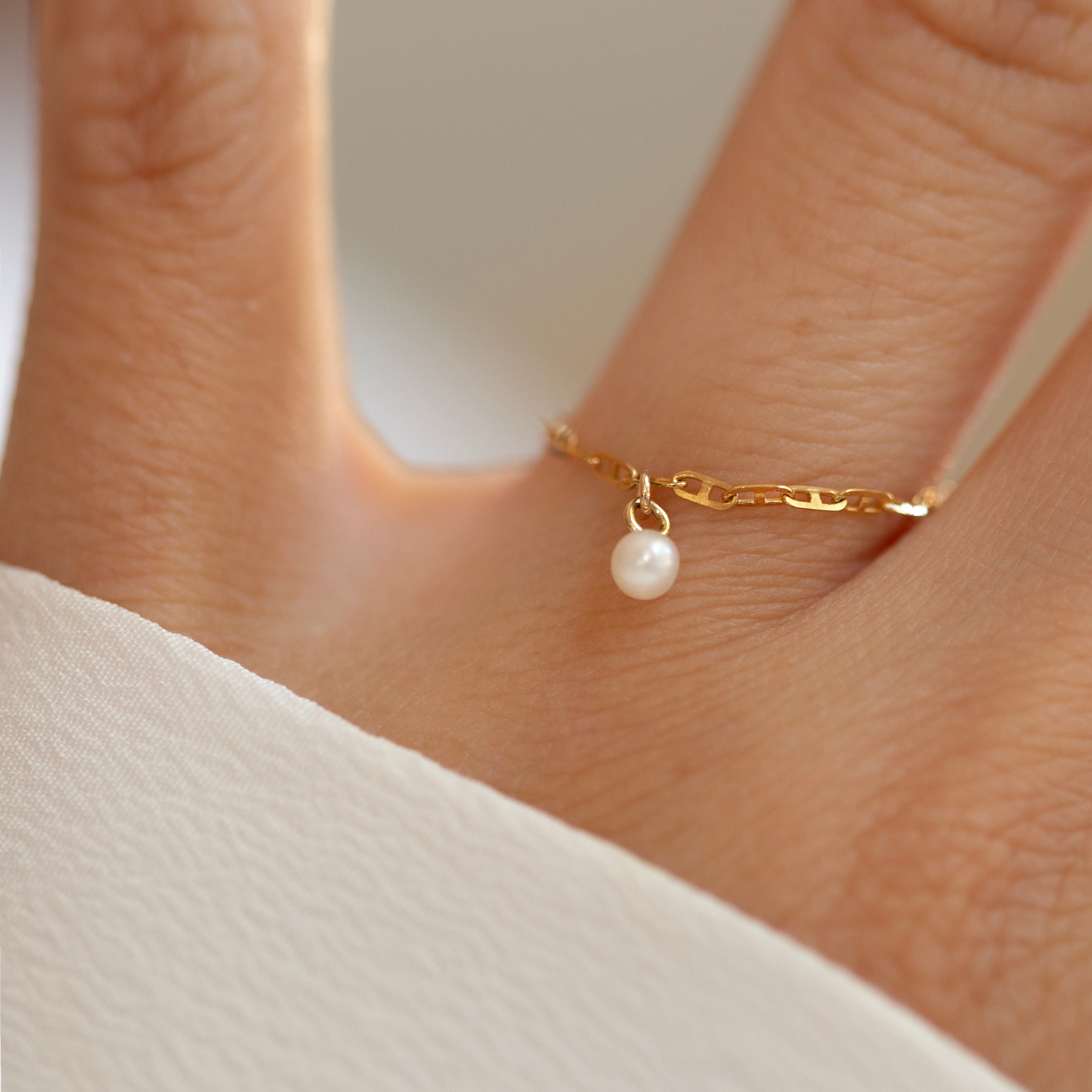This 14k Solid Gold Chain Ring features a delicate link design and a dainty dangling pearl, creating a modern yet timeless accessory. Worn solo or paired with other rings, it adds a touch of elegance to any look