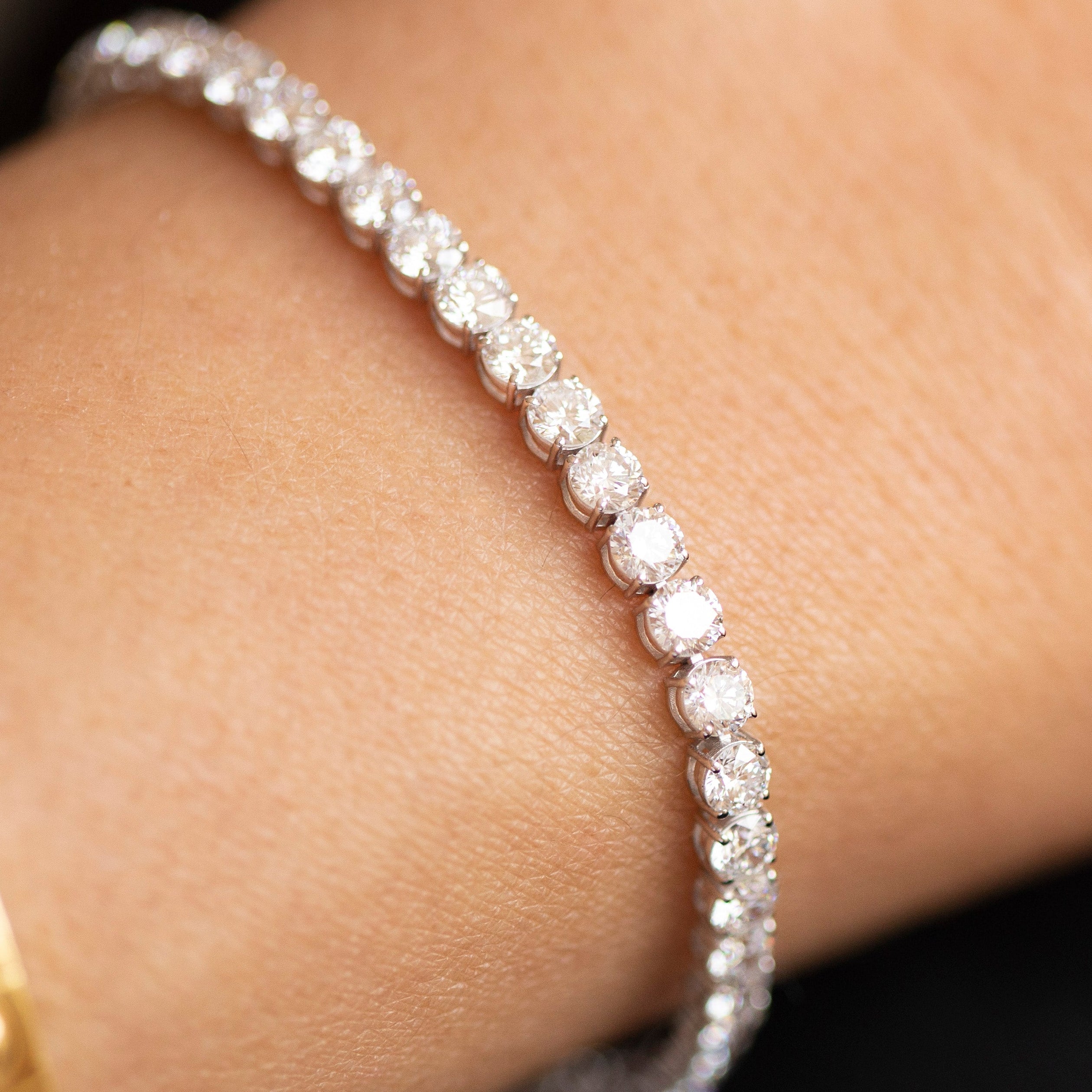 Diamond bracelet on a wrist with a gold watch, close-up view.