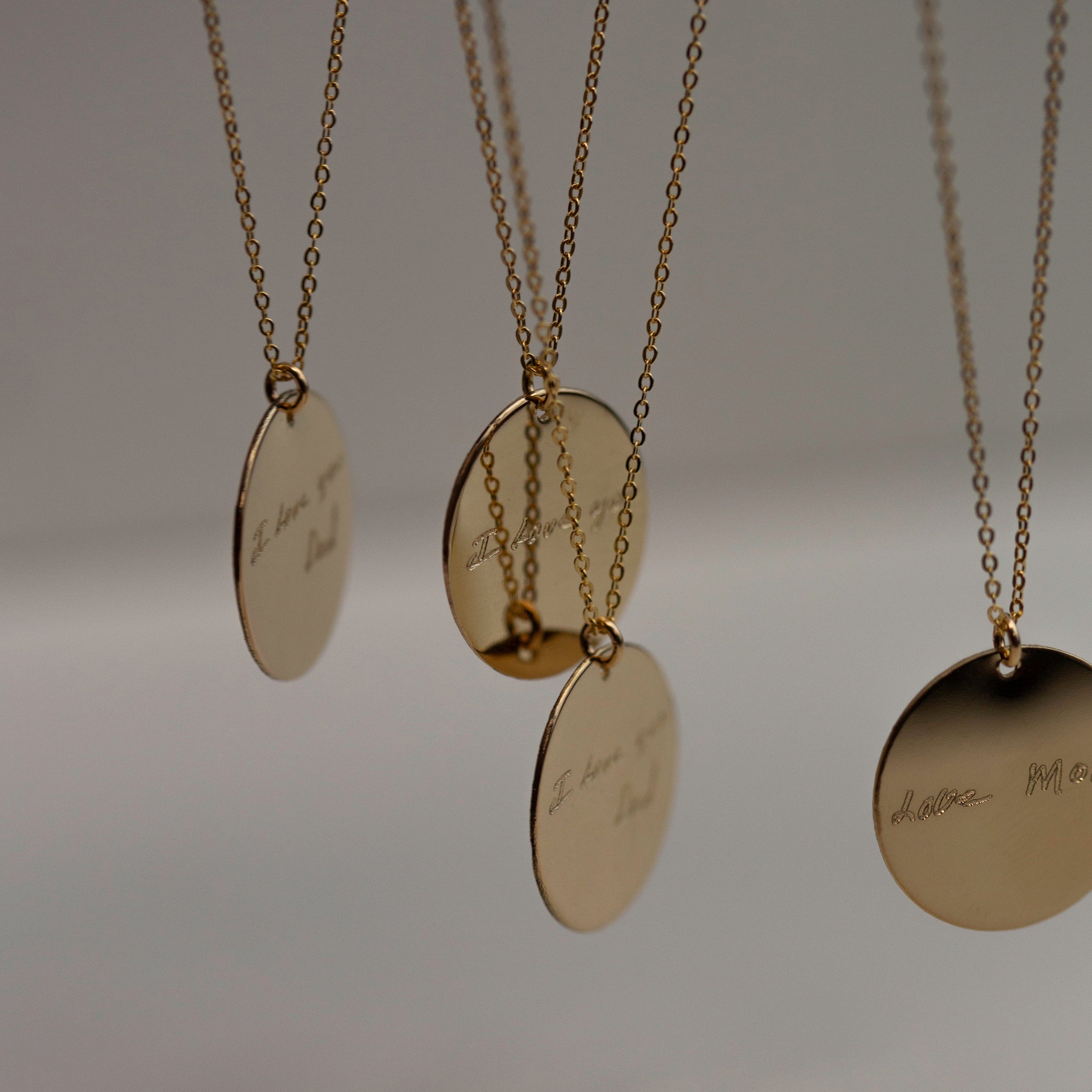 A gold chain necklace with a round, gold pendant.