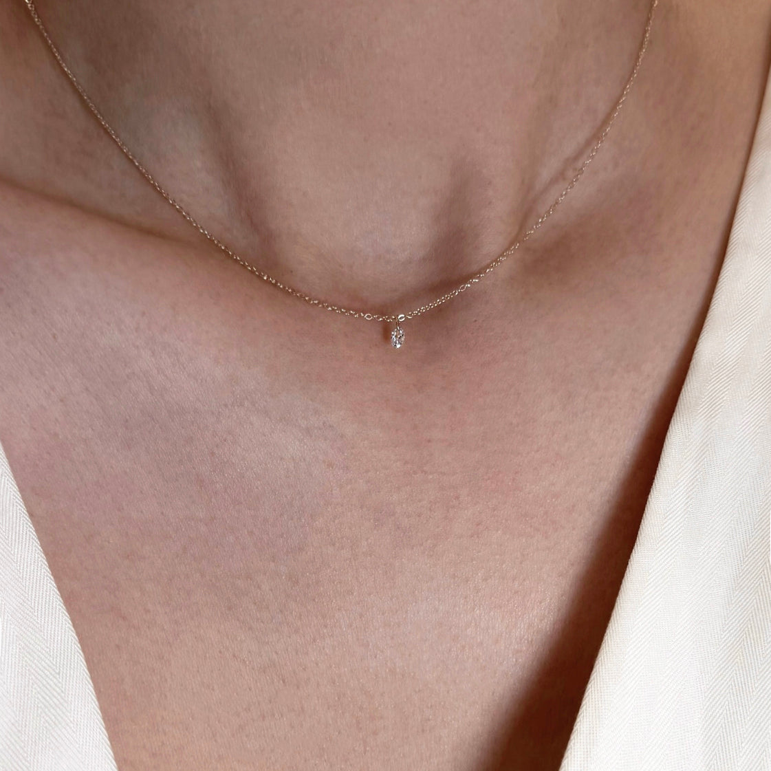 yellow gold necklace with a small diamond pendant on a neutral background