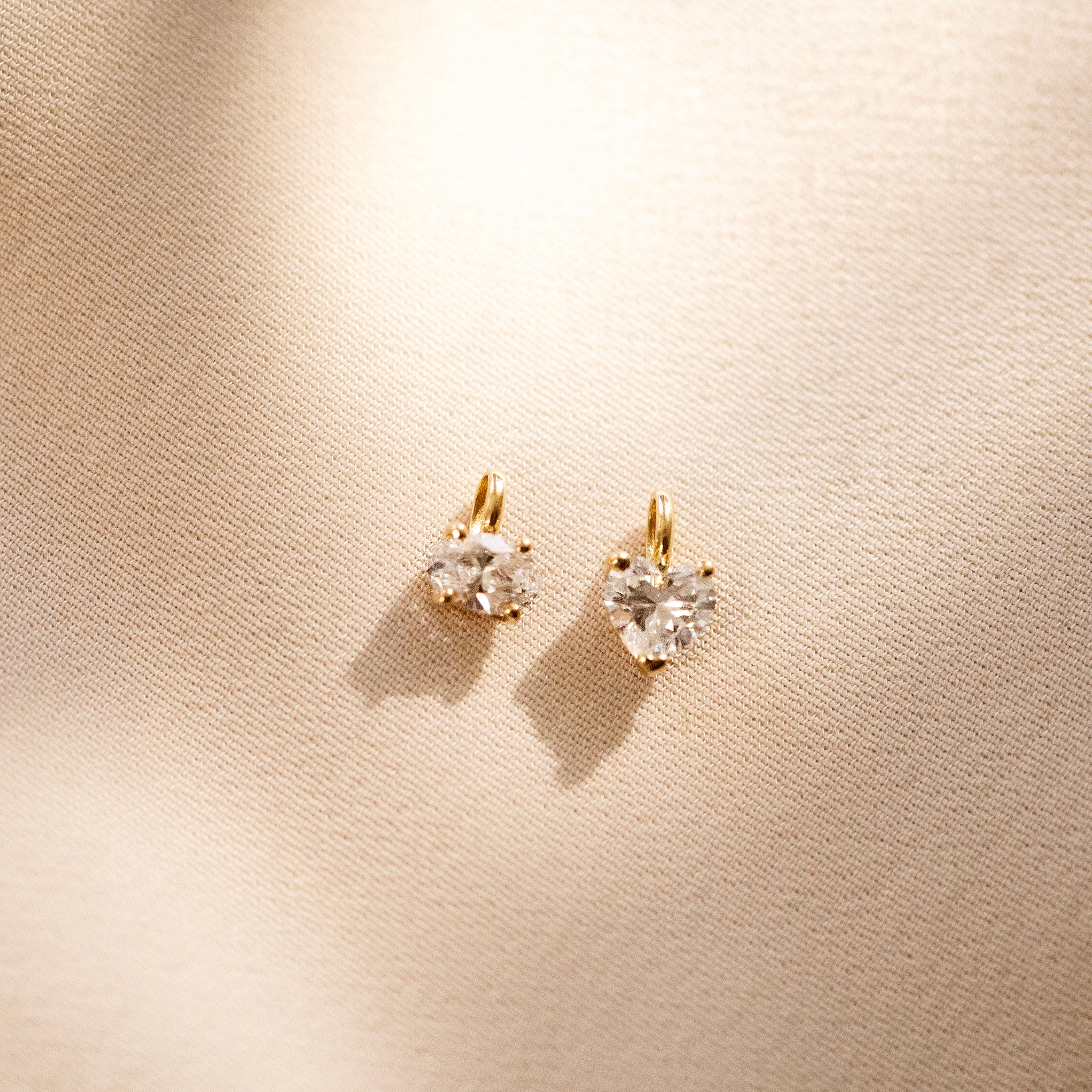 Heart-shaped diamond earrings on a beige background