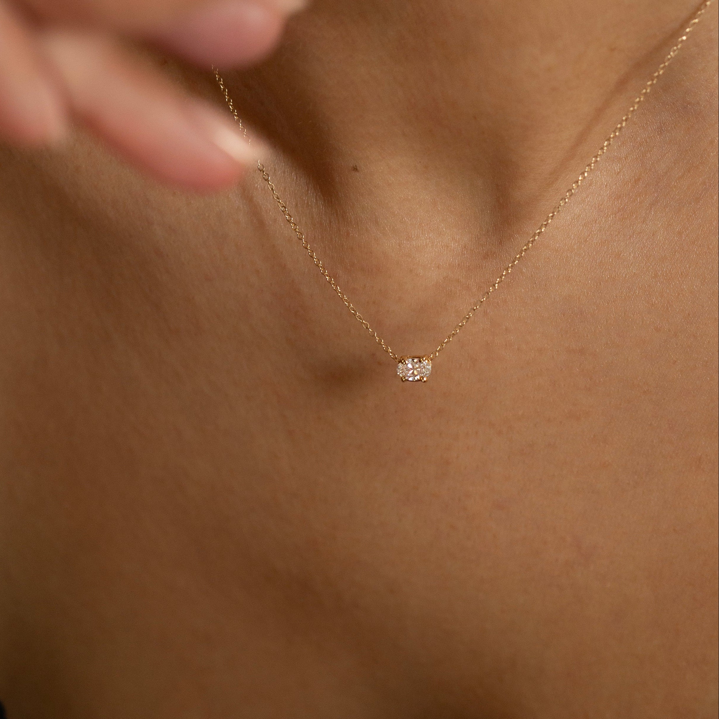 Gold necklace with a small pendant on a person's neck