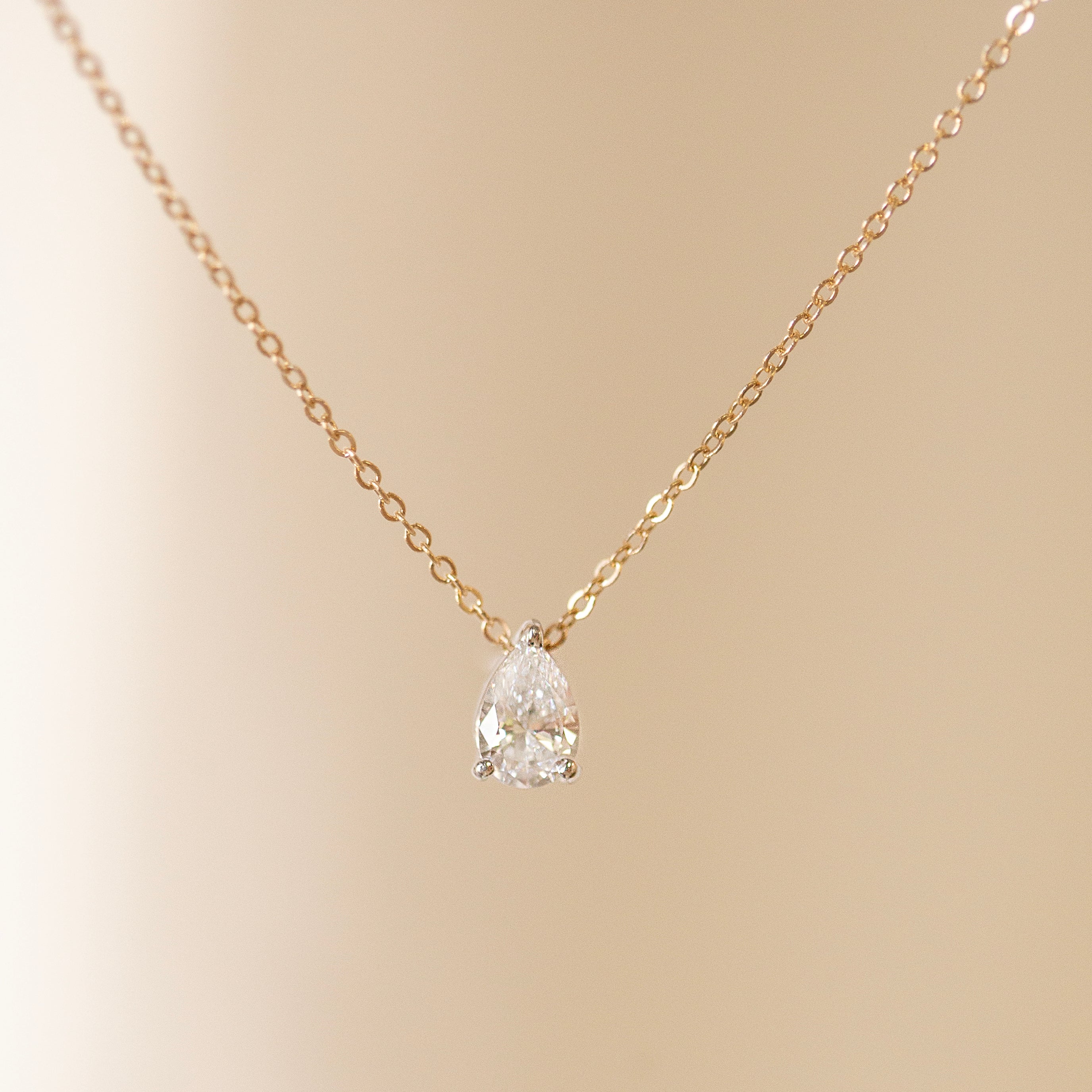 Gold necklace with a white gold setting on a beige background