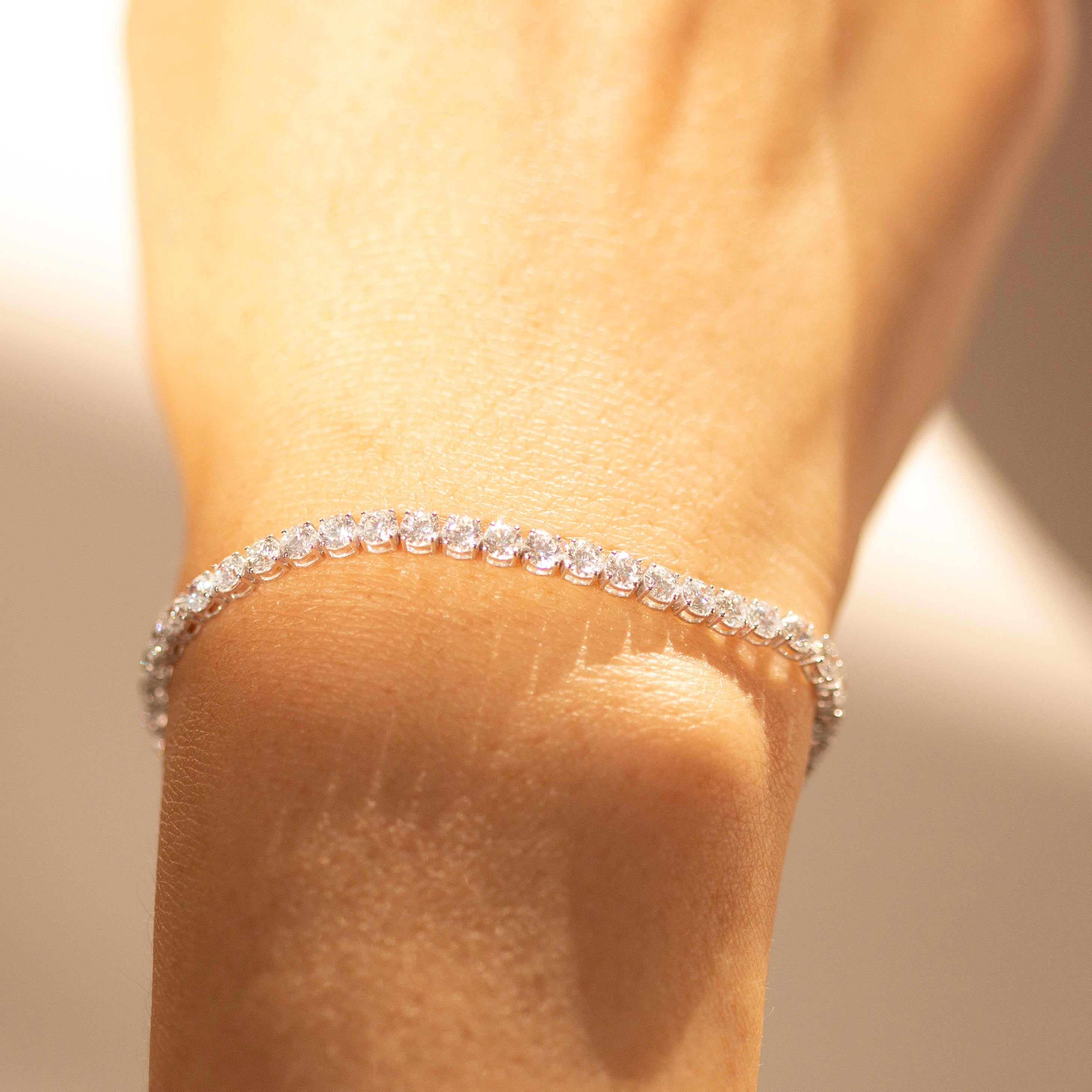 diamond tennis bracelet on a wrist with a blurred background