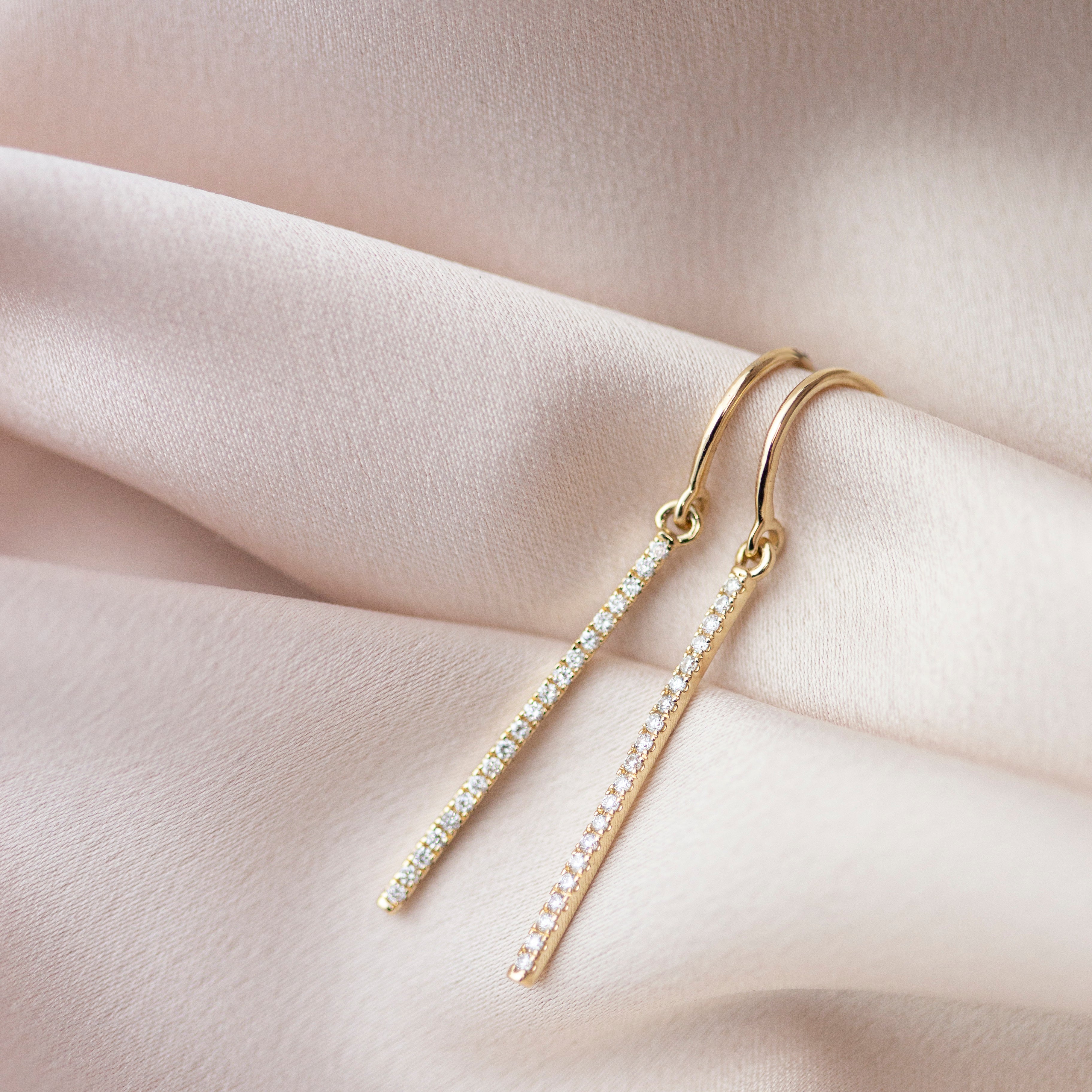 These exquisite 14k gold drop bar earrings feature genuine diamonds, adding a modern touch to their versatile design. A must-have for those seeking a timeless and sophisticated accessory.