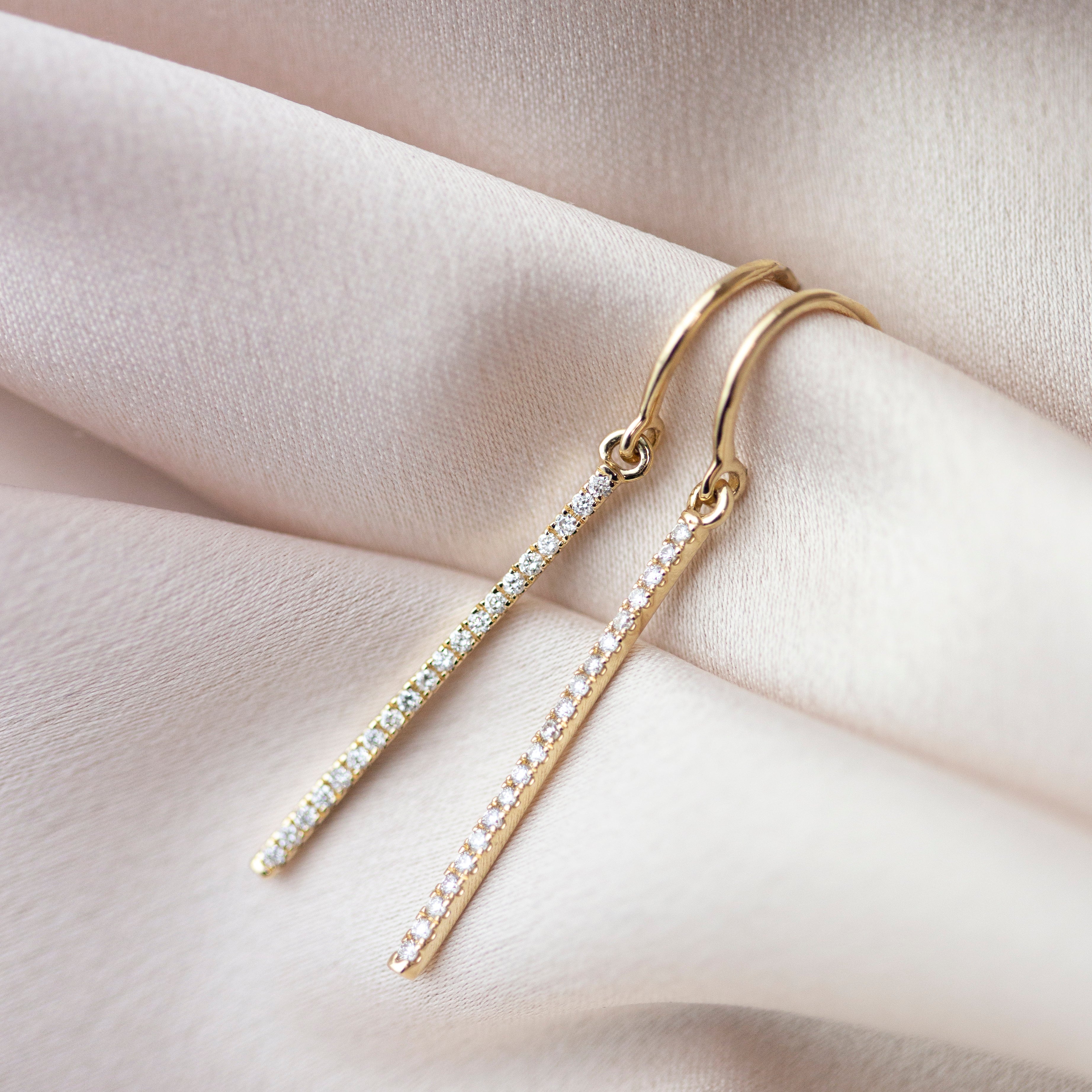 These exquisite 14k gold drop bar earrings feature genuine diamonds, adding a modern touch to their versatile design. A must-have for those seeking a timeless and sophisticated accessory.