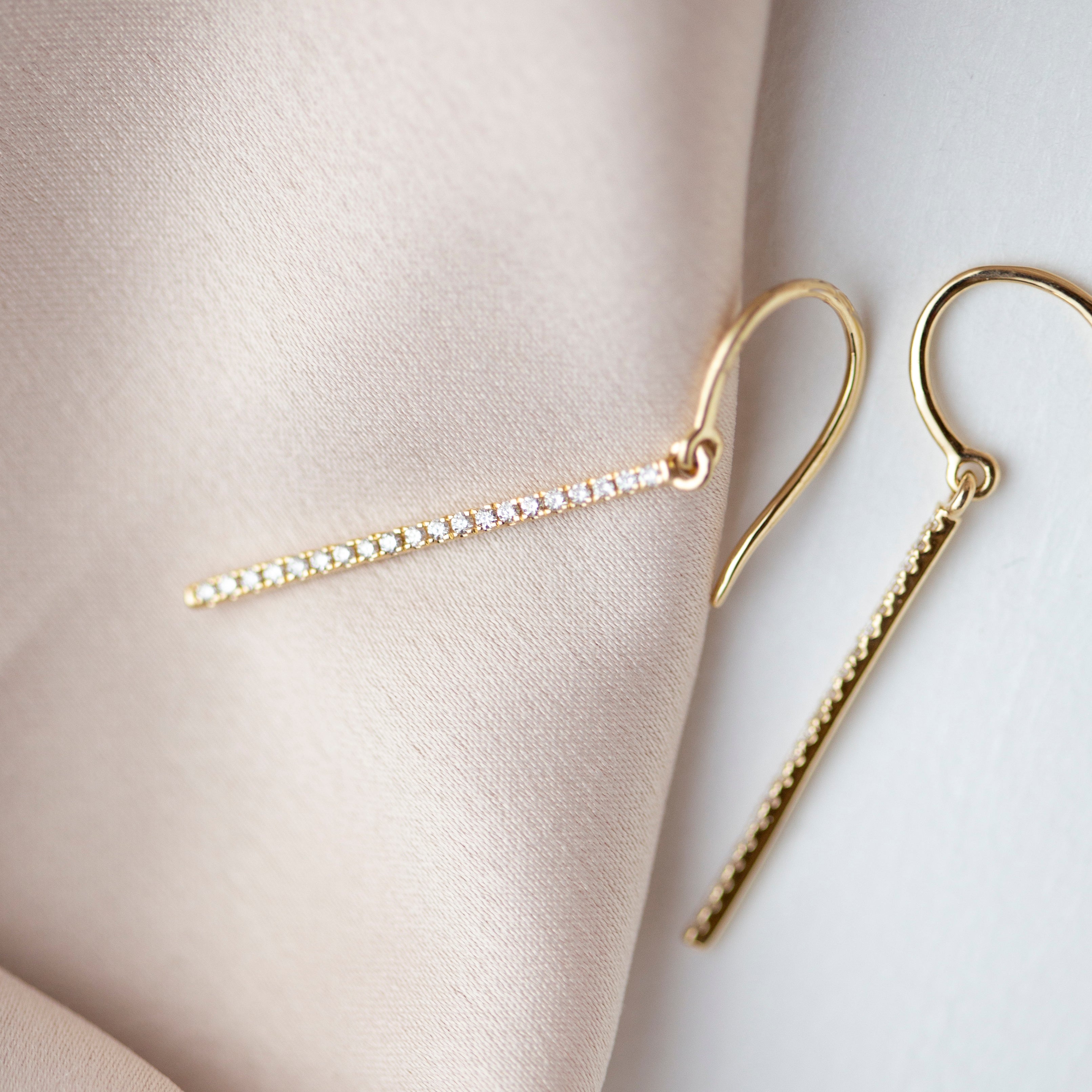 These exquisite 14k gold drop bar earrings feature genuine diamonds, adding a modern touch to their versatile design. A must-have for those seeking a timeless and sophisticated accessory.