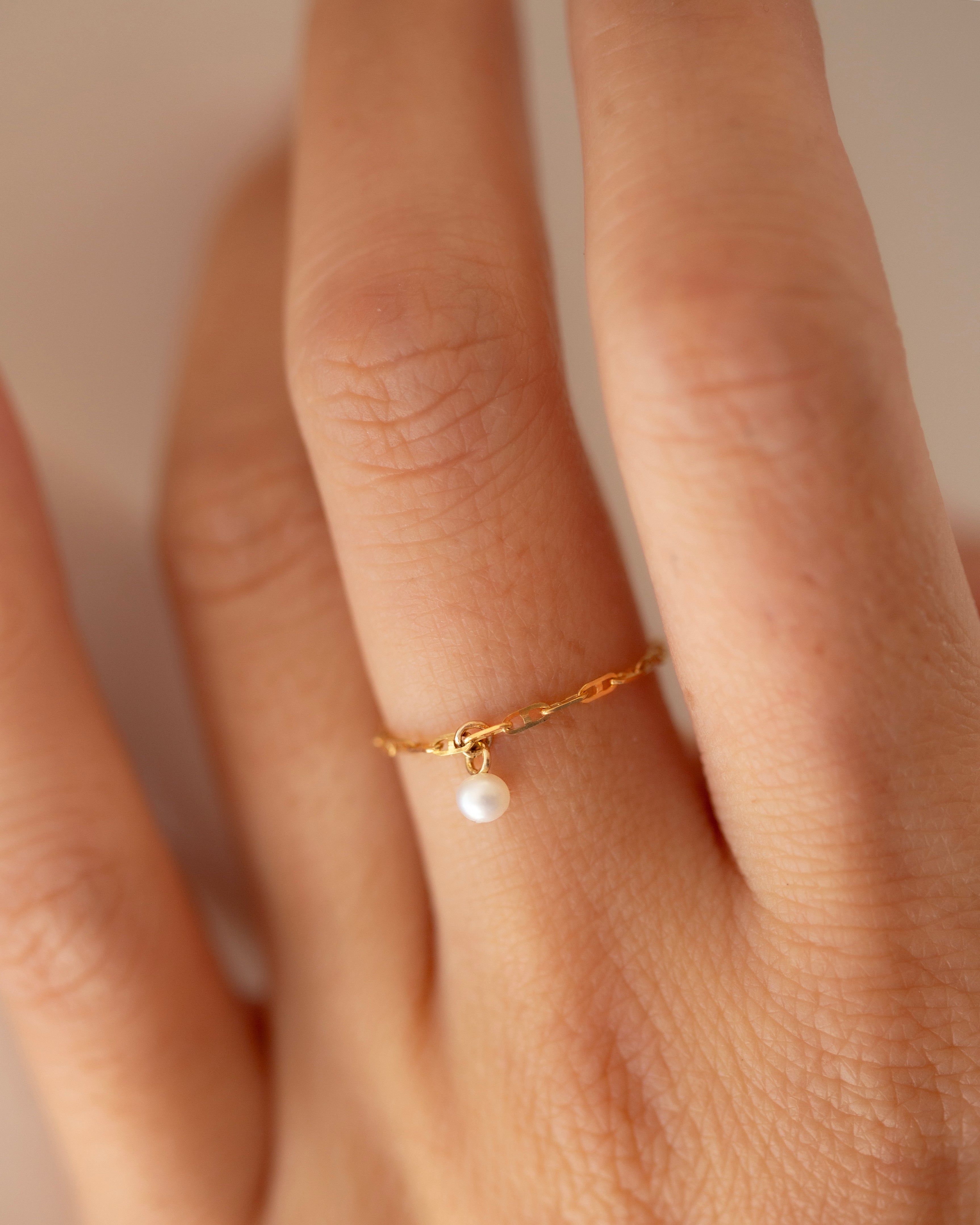 This 14k Solid Gold Chain Ring features a delicate link design and a dainty dangling pearl, creating a modern yet timeless accessory. Worn solo or paired with other rings, it adds a touch of elegance to any look