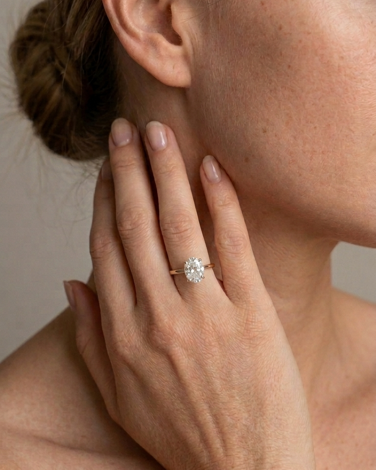 Close-up of a hand wearing a diamond ring with a neutral background