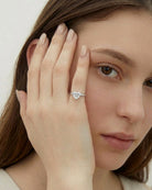 Woman wearing a diamond ring on her finger with a neutral background