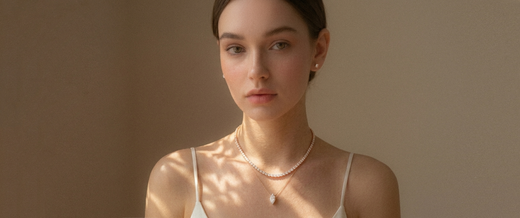Woman wearing a delicate necklace against a neutral background