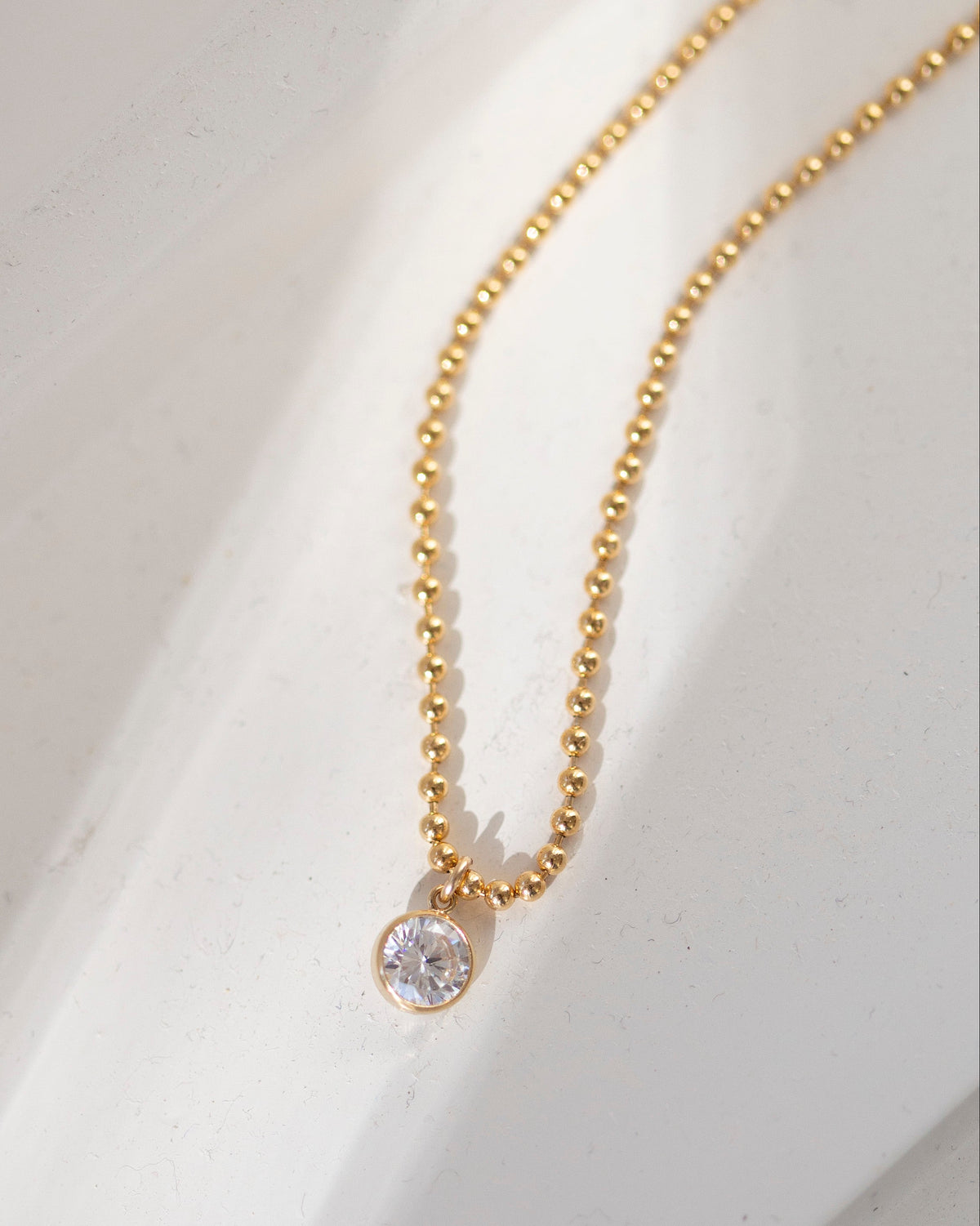 Gold necklace with a diamond pendant on a white background