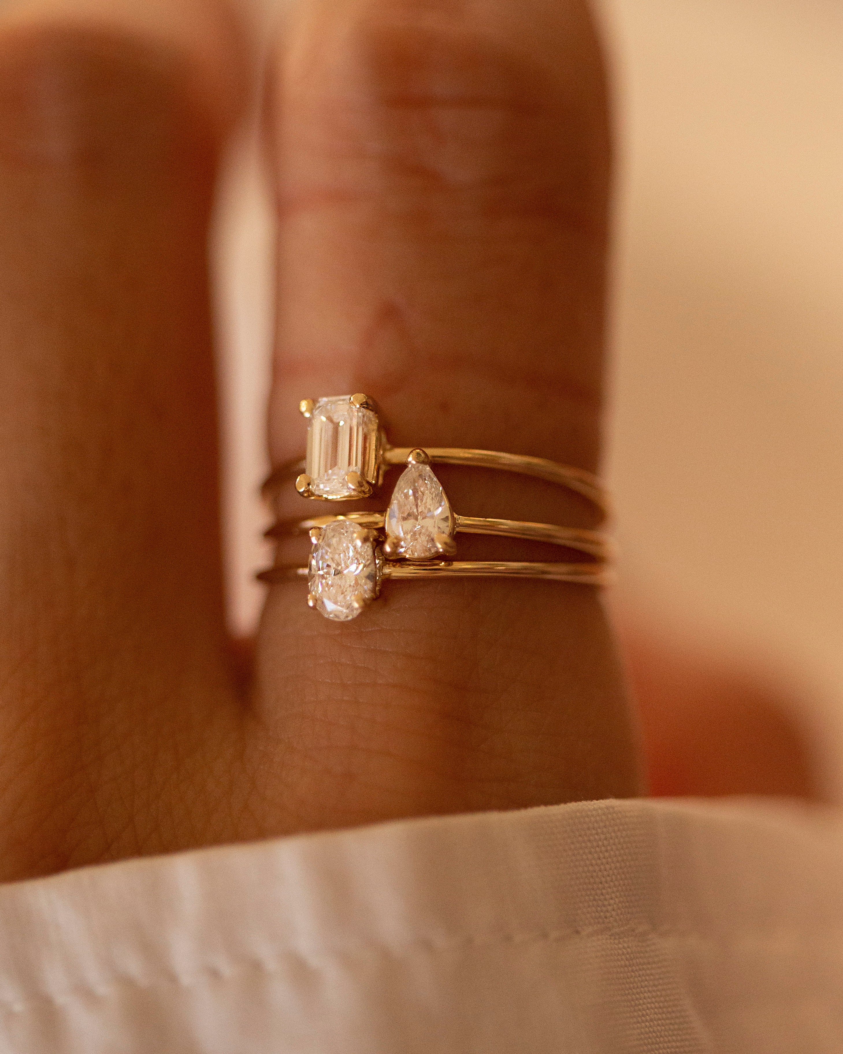 Three gold rings with diamonds on a hand against a neutral background