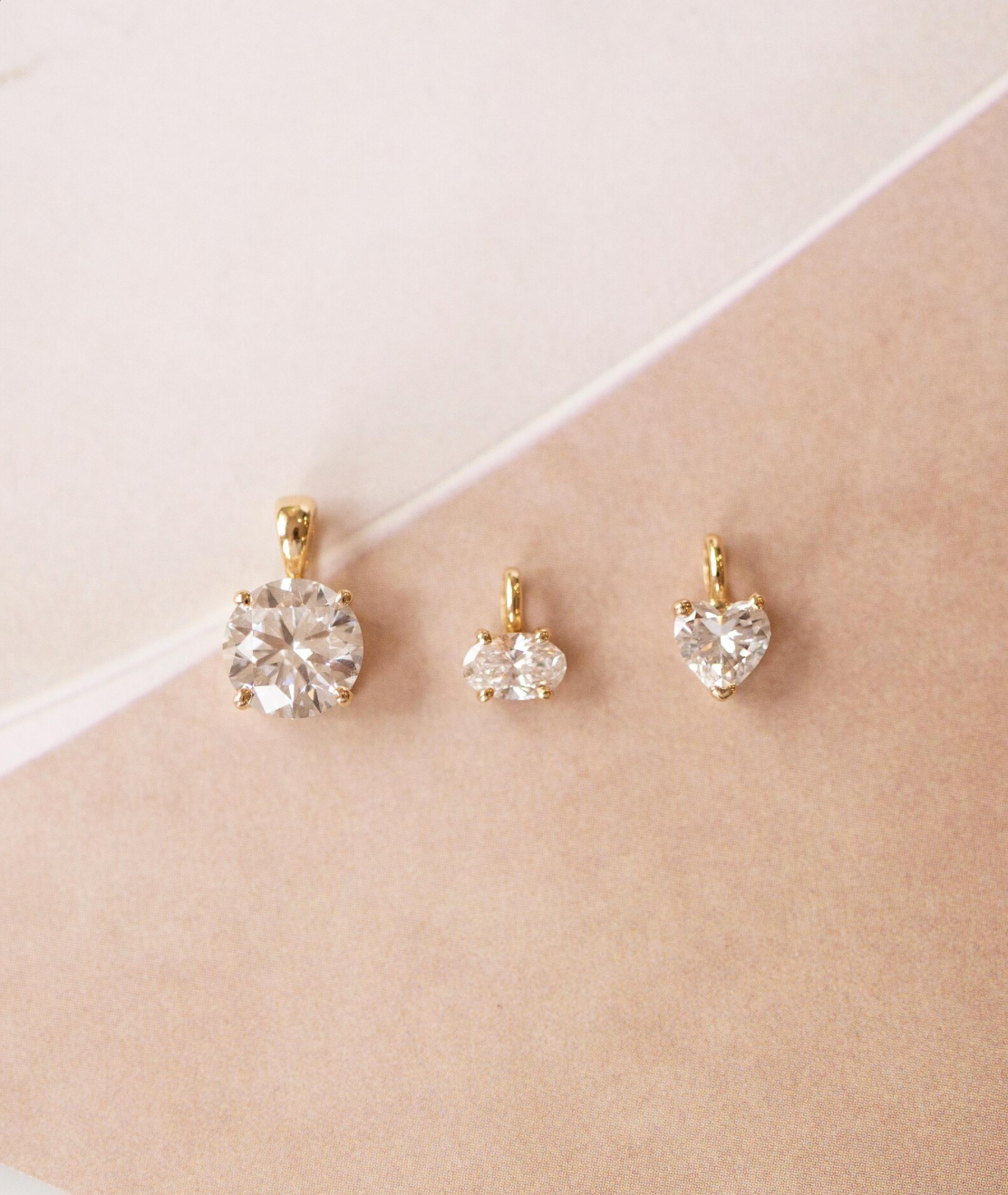 Set of gold earrings with clear gemstones on a beige surface