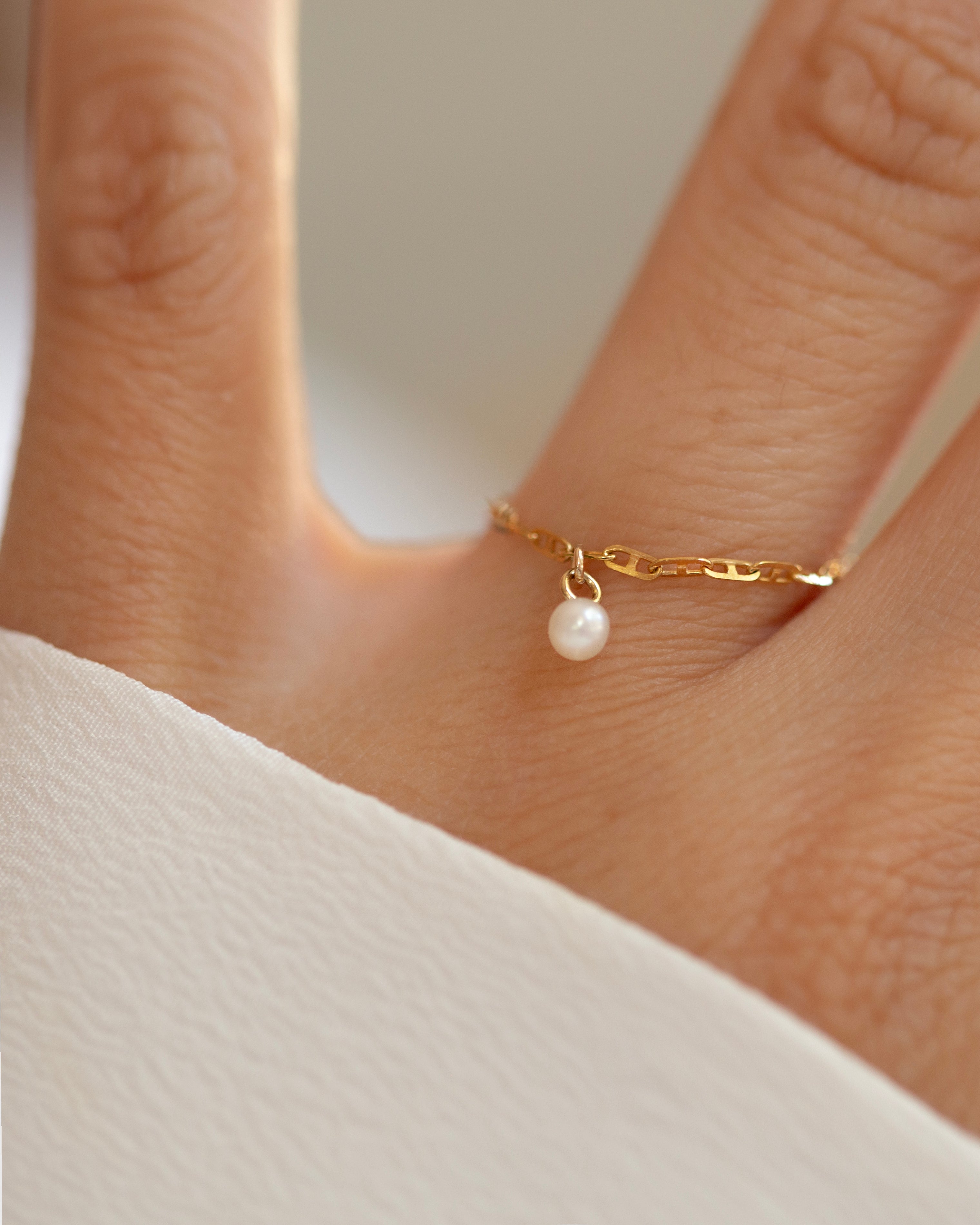 This 14k Solid Gold Chain Ring features a delicate link design and a dainty dangling pearl, creating a modern yet timeless accessory. Worn solo or paired with other rings, it adds a touch of elegance to any look