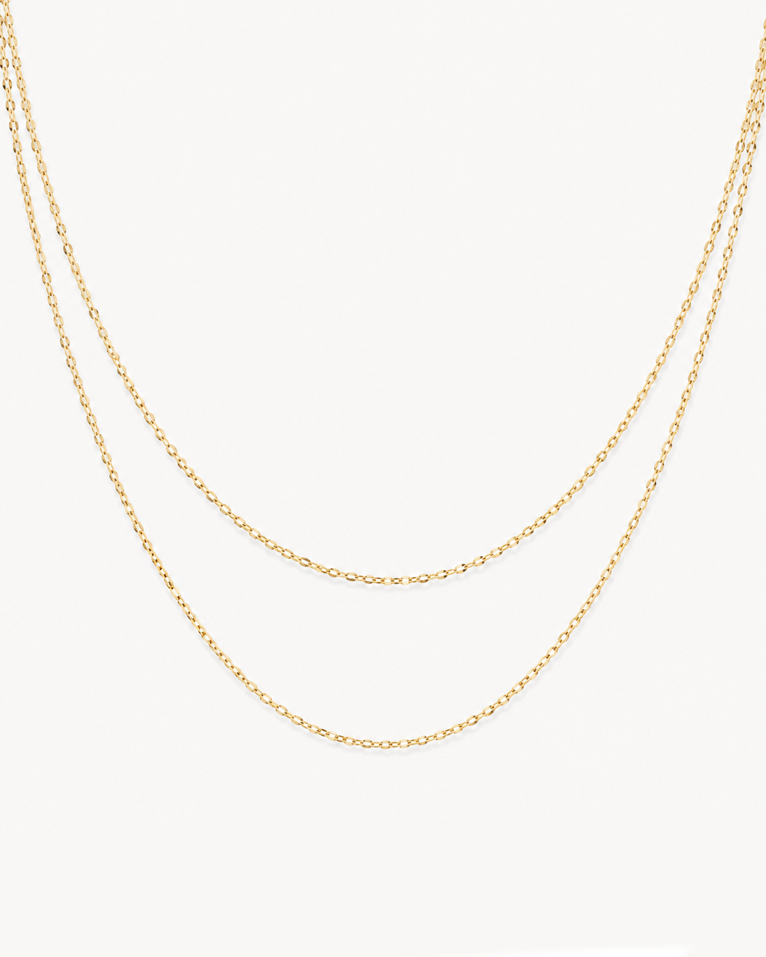 A delicate double-layered gold chain necklace displayed against a clean, off-white background.