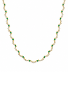 A gold necklace featuring a repeating wave pattern of small green emerald-cut stones and clear round-cut stones, displayed on a solid white background.