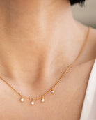 Gold necklace with small pendants on a person's neck