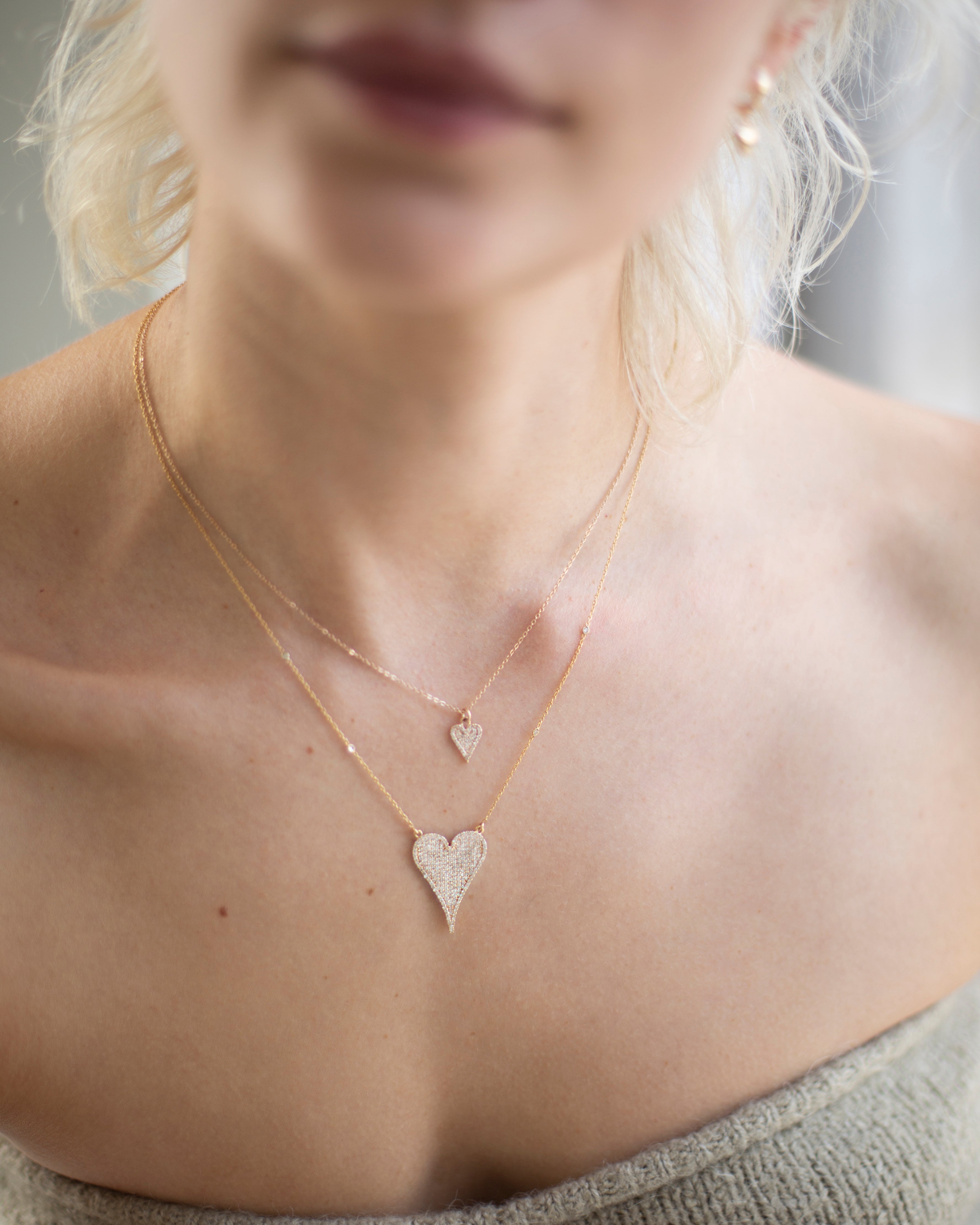 Close-up of a person wearing two heart-shaped necklaces.