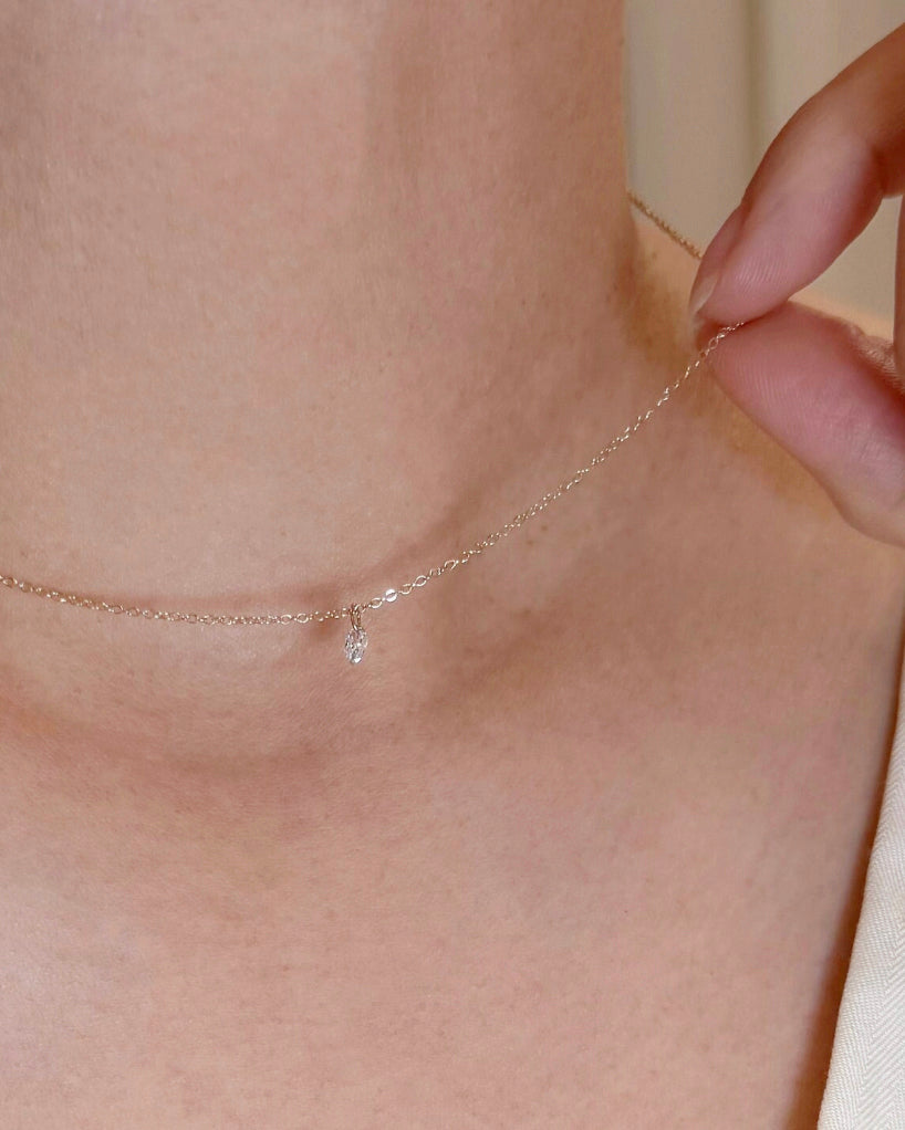 Close-up of a delicate necklace being worn on a person's neck.
