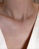 yellow gold necklace with a small diamond pendant on a neutral background