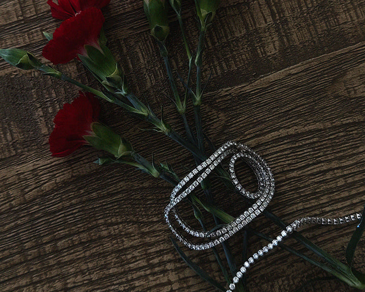 Red flowers with a silver bracelet on a wooden surface