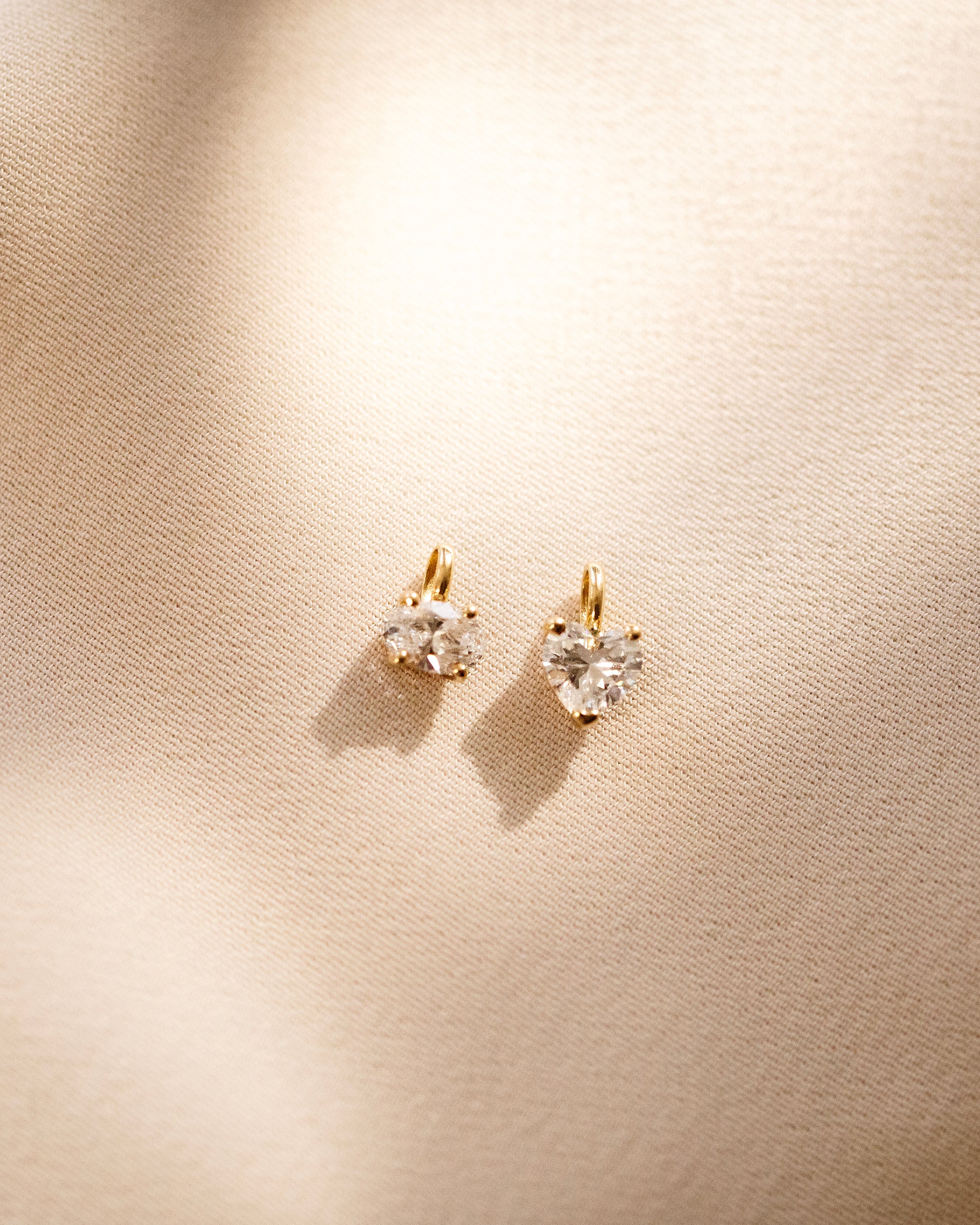 Heart-shaped diamond earrings on a beige background