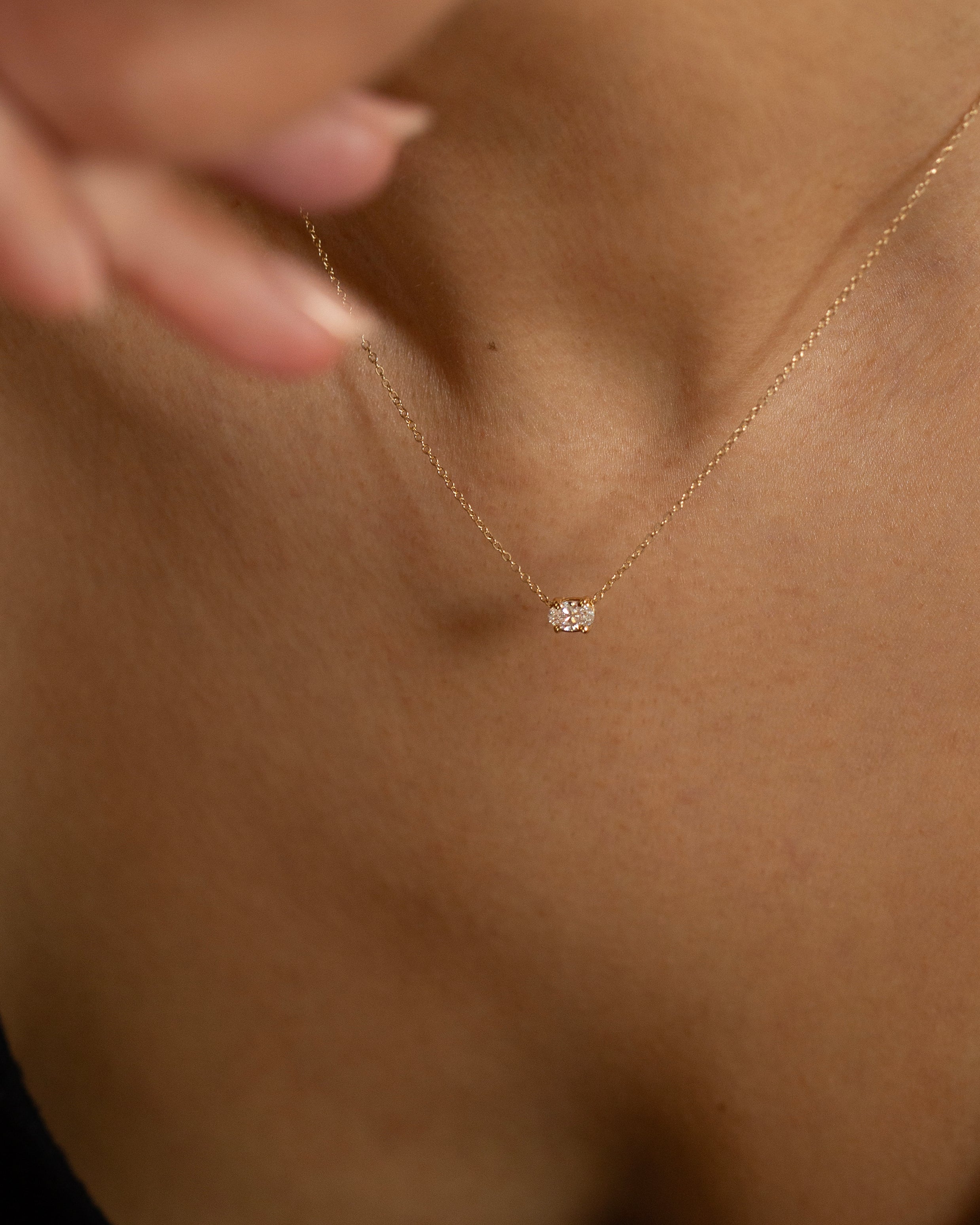 Gold necklace with a small pendant on a person's neck