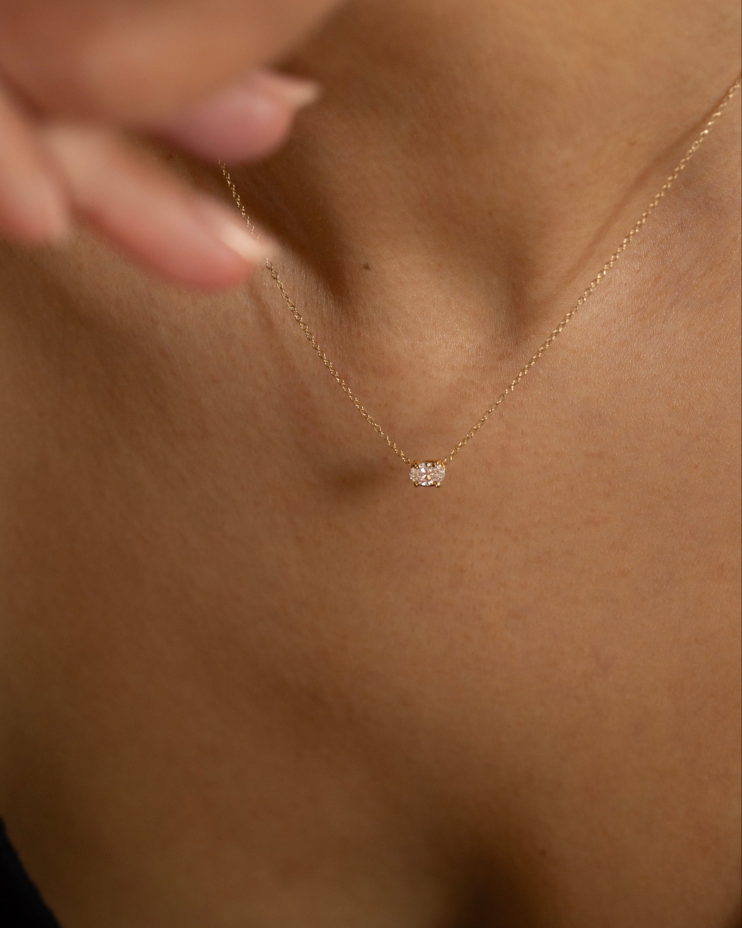 Gold necklace with a small pendant on a person's neck