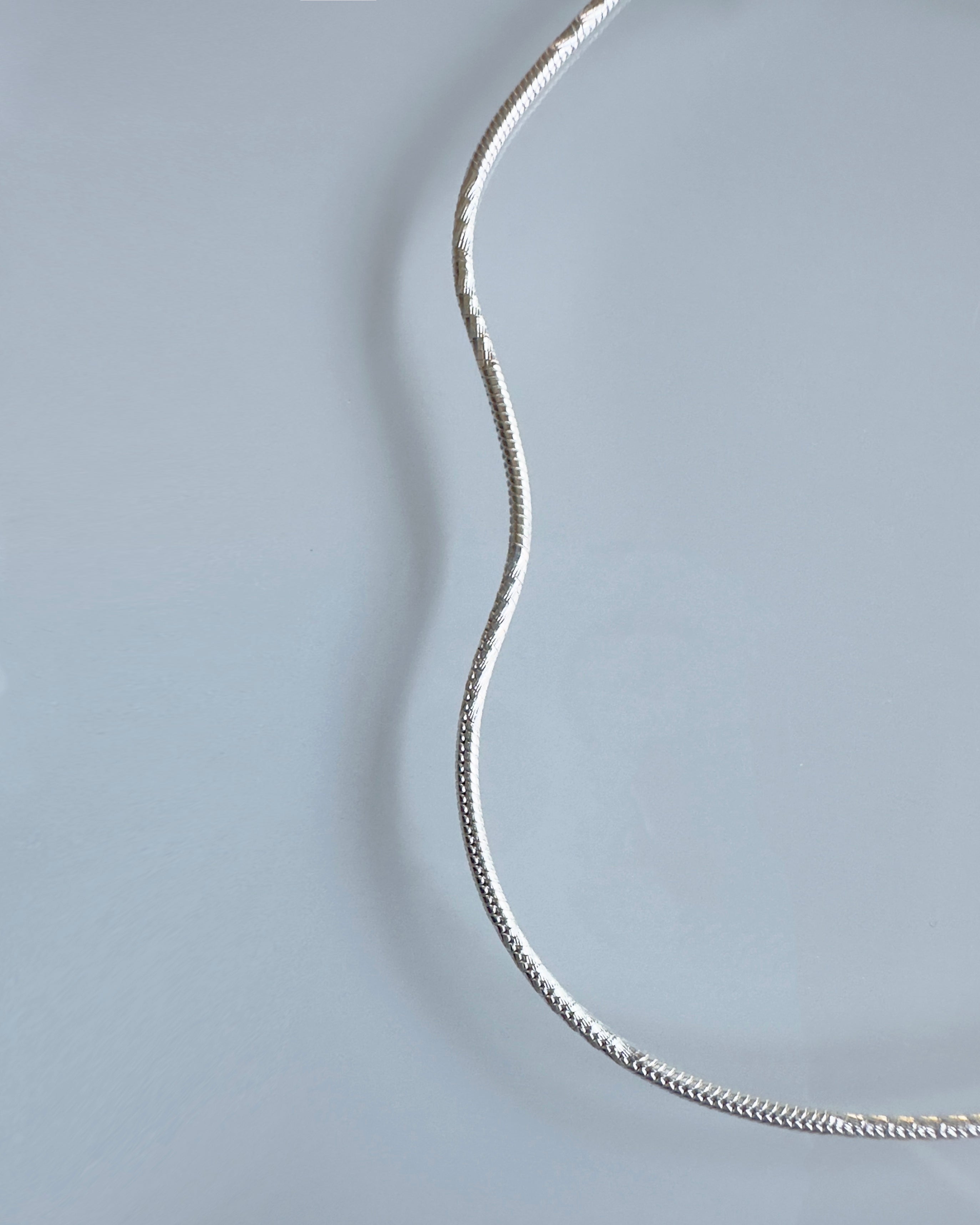 Silver chain anklet on a light gray background