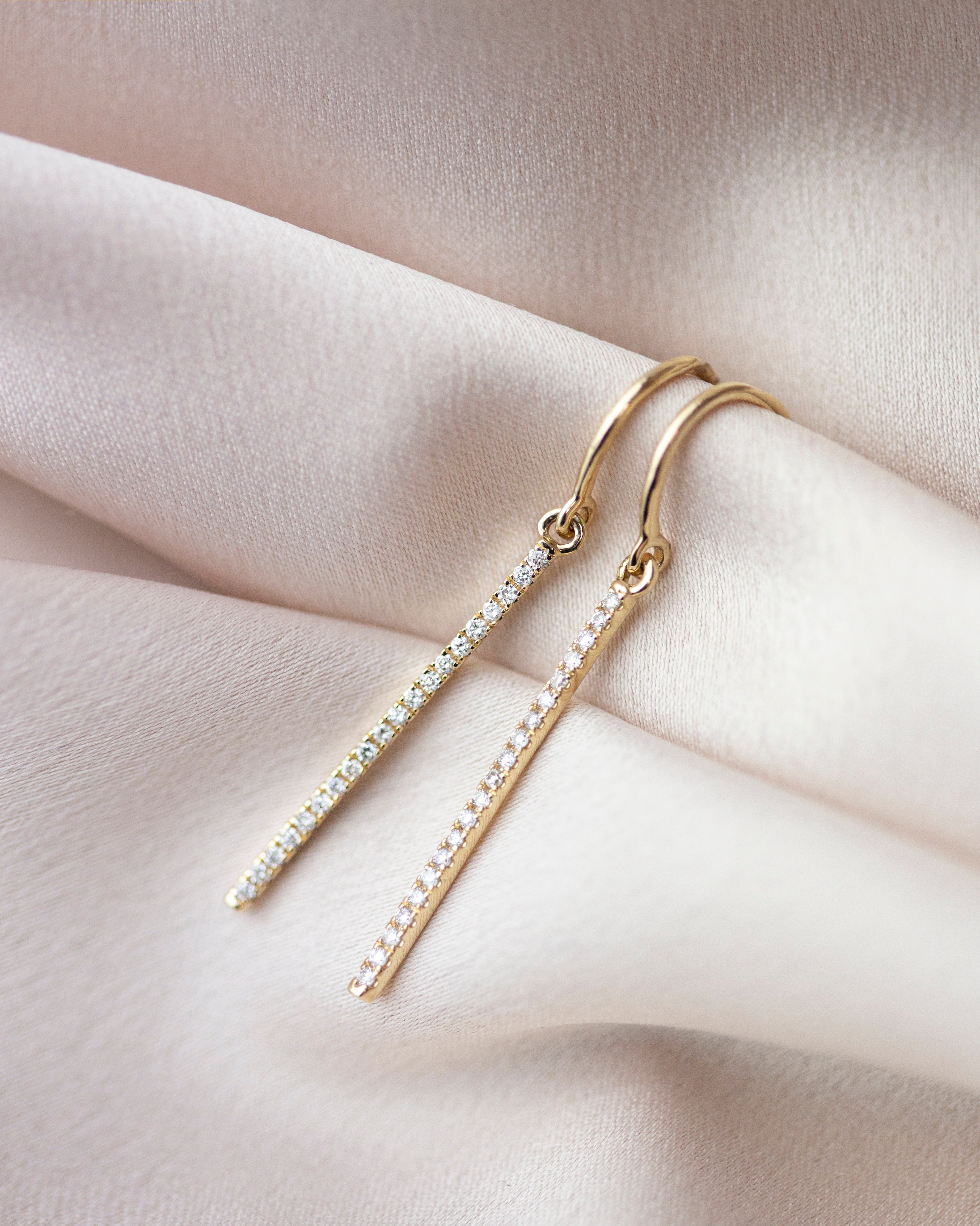 These exquisite 14k gold drop bar earrings feature genuine diamonds, adding a modern touch to their versatile design. A must-have for those seeking a timeless and sophisticated accessory.