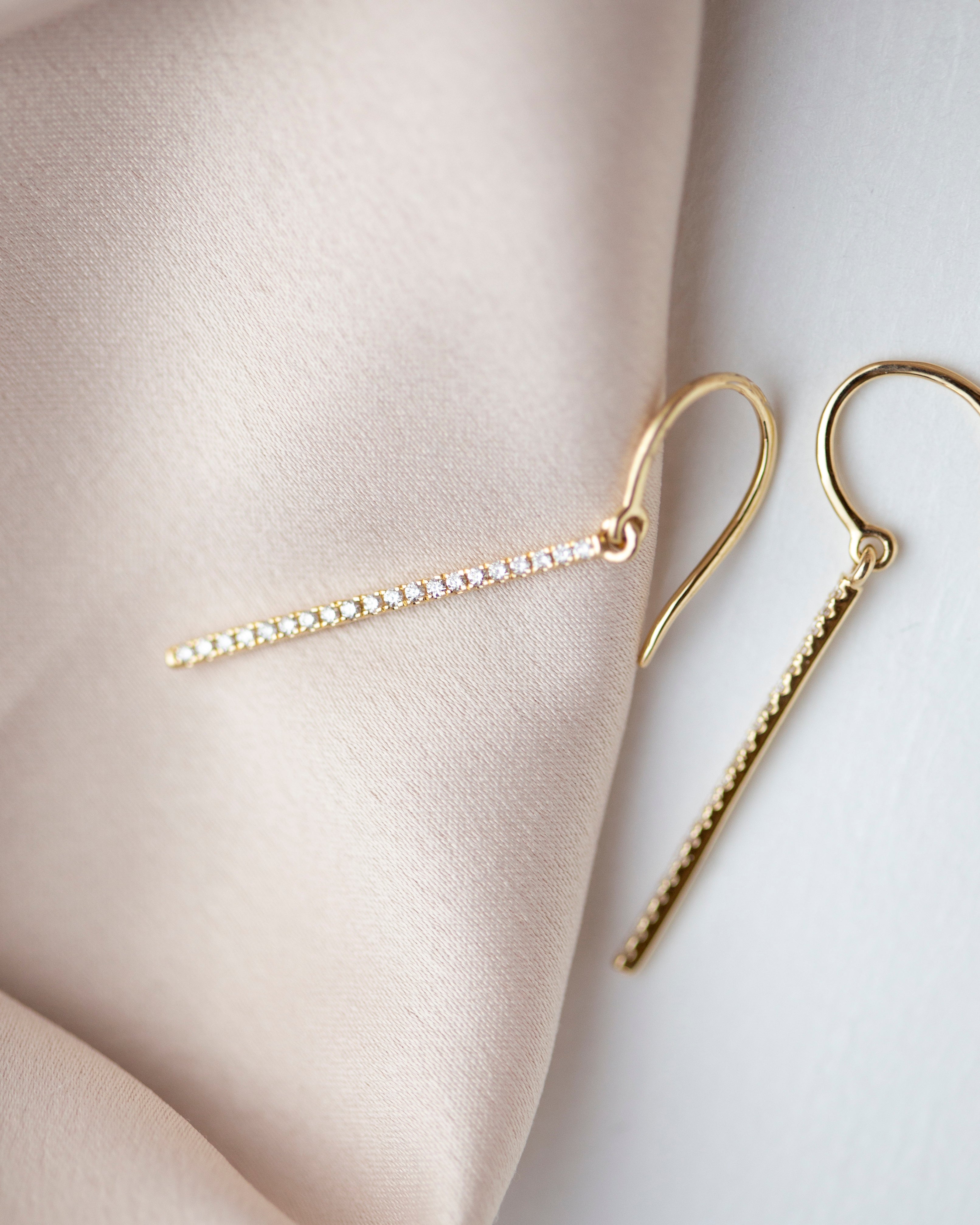 These exquisite 14k gold drop bar earrings feature genuine diamonds, adding a modern touch to their versatile design. A must-have for those seeking a timeless and sophisticated accessory.